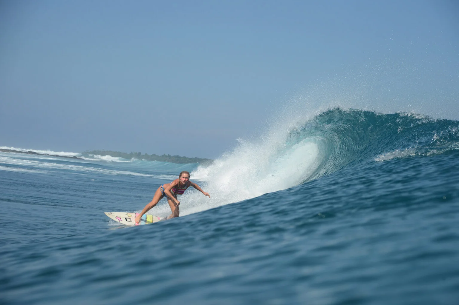 Surfista recorriendo una ola azul en Indonesia