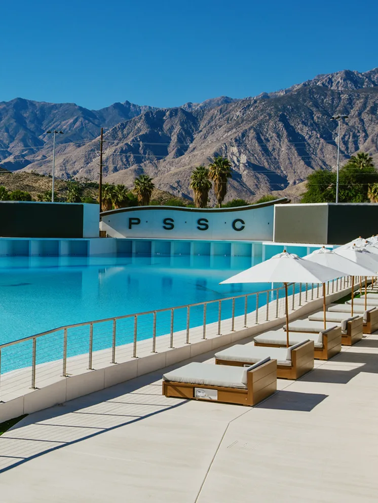 Piscina de olas y camastros de Palm Springs Surf Club frente a las montañas